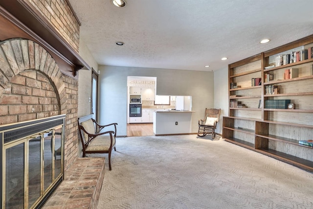 living area with light carpet, a brick fireplace, and a textured ceiling