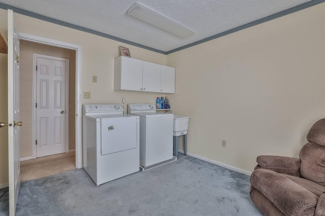 laundry area with cabinets, light carpet, washer and dryer, and a textured ceiling