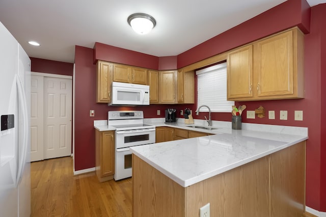 kitchen featuring sink, light stone counters, kitchen peninsula, white appliances, and light hardwood / wood-style flooring