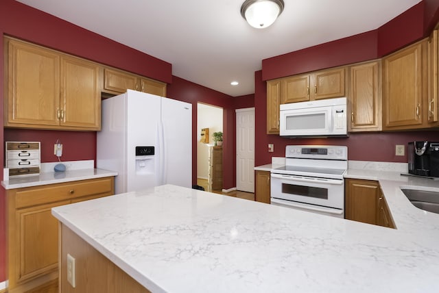 kitchen with white appliances, light stone countertops, and sink