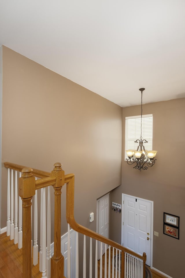 staircase with wood-type flooring and a chandelier