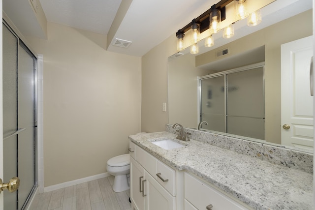 bathroom featuring vanity, an enclosed shower, and toilet