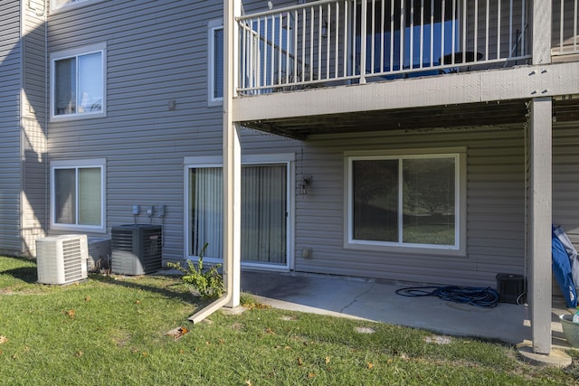 rear view of property with cooling unit, a balcony, and a patio