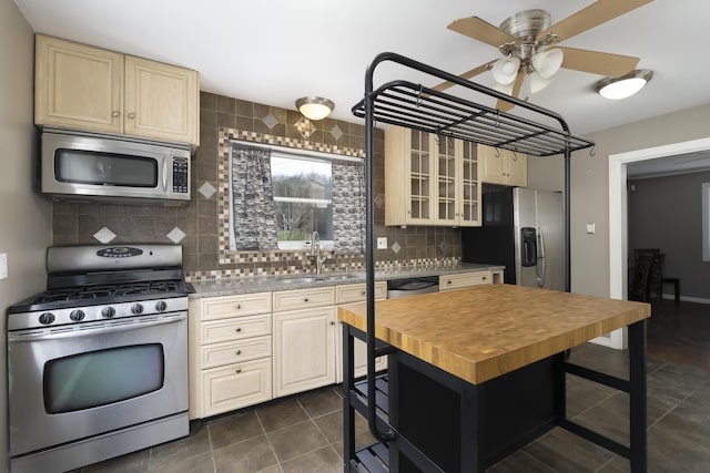 kitchen with sink, dark tile patterned floors, stainless steel appliances, tasteful backsplash, and cream cabinets