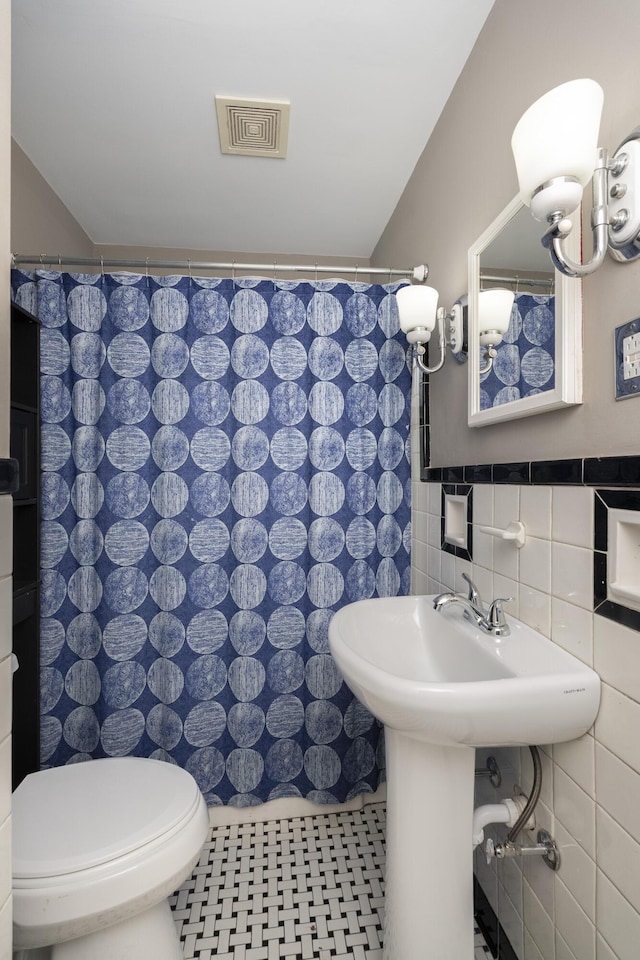 bathroom with tile patterned flooring, tile walls, and toilet