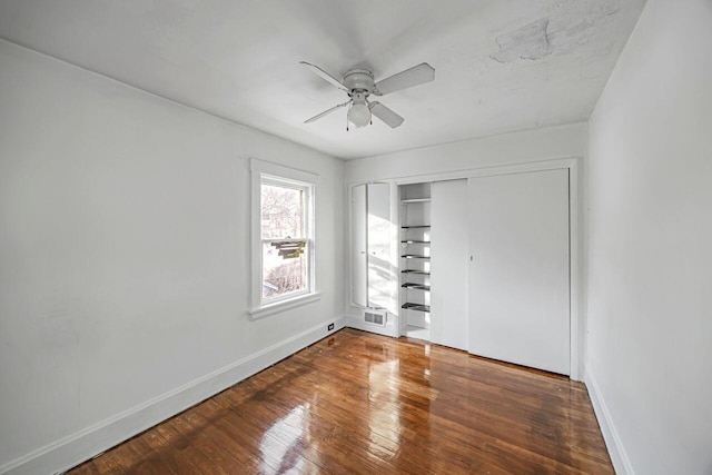 unfurnished bedroom with ceiling fan, dark hardwood / wood-style flooring, and a closet