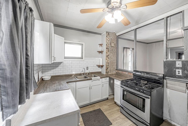 kitchen with sink, gas range, crown molding, decorative backsplash, and white cabinets