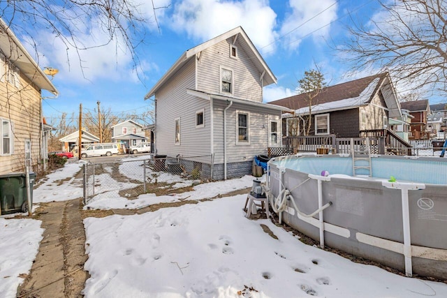 snow covered house with a pool side deck