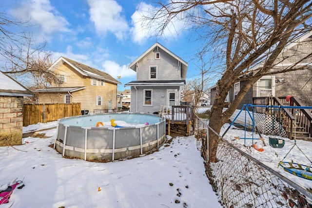 snow covered back of property featuring a playground