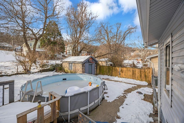 yard layered in snow featuring a fenced in pool and a storage unit