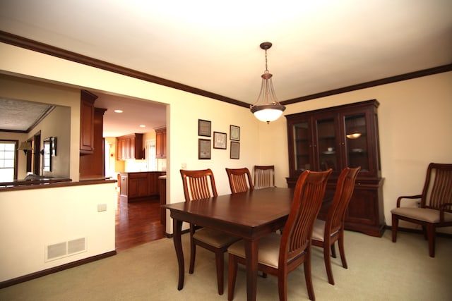 dining room with crown molding and light colored carpet