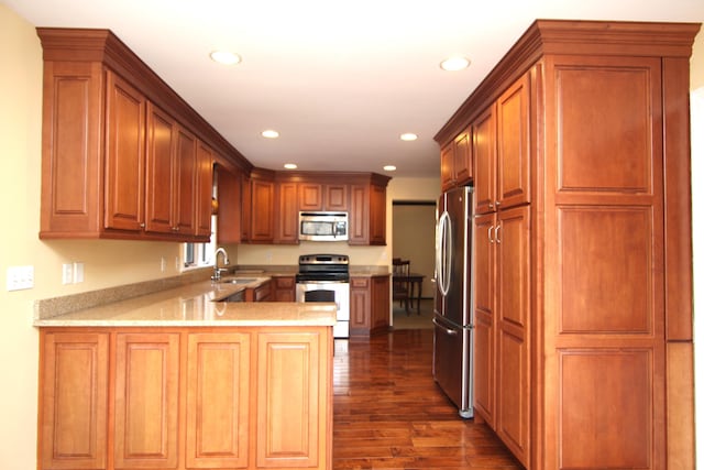 kitchen with sink, dark hardwood / wood-style floors, kitchen peninsula, and appliances with stainless steel finishes