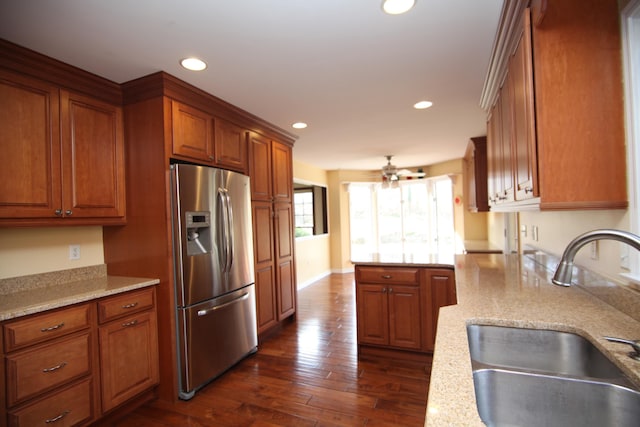 kitchen with dark hardwood / wood-style floors, sink, stainless steel fridge, ceiling fan, and light stone countertops