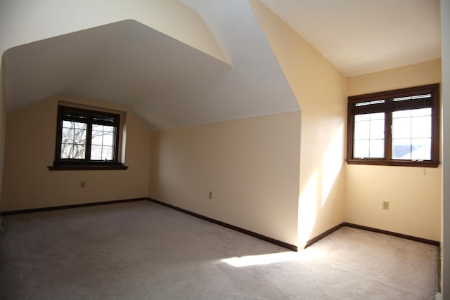 additional living space with light colored carpet and vaulted ceiling