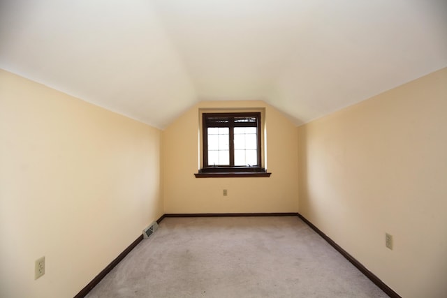 additional living space featuring lofted ceiling and light carpet