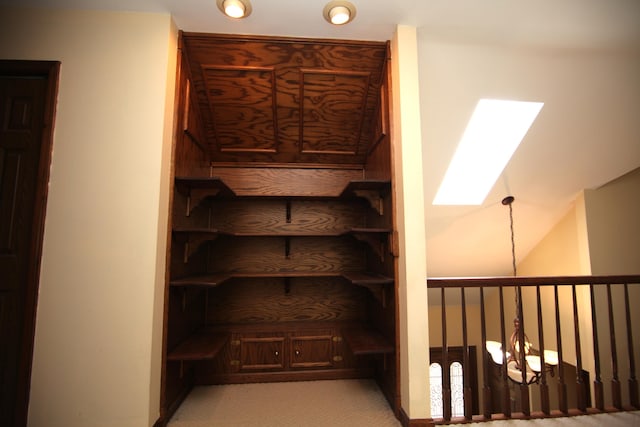 staircase featuring lofted ceiling with skylight, a chandelier, and carpet