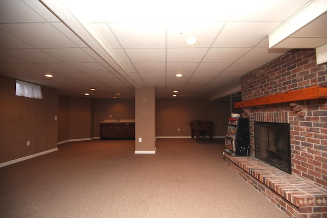 basement with a brick fireplace, sink, a drop ceiling, and carpet