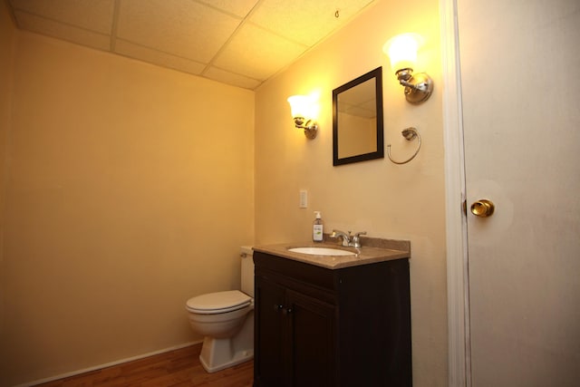 bathroom featuring hardwood / wood-style floors, vanity, a paneled ceiling, and toilet