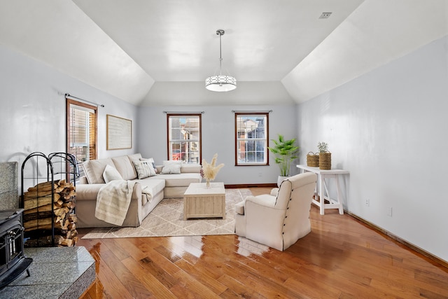 living room with lofted ceiling, a wood stove, and light wood-type flooring