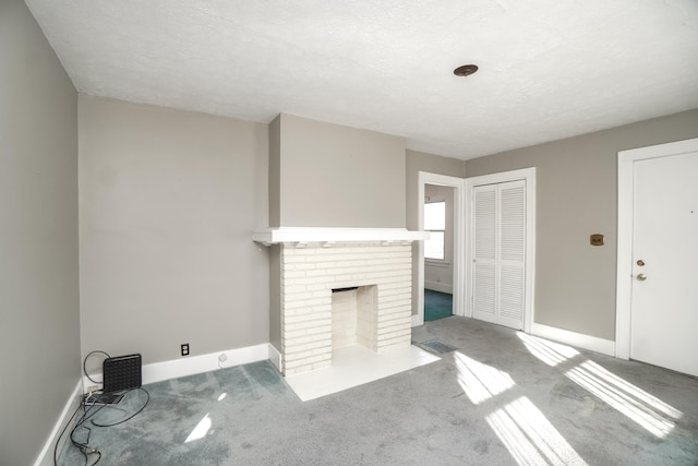 unfurnished living room with carpet floors, a brick fireplace, and a textured ceiling