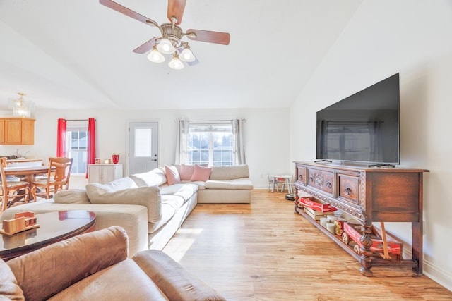 living room featuring light wood-style flooring, baseboards, lofted ceiling, and ceiling fan