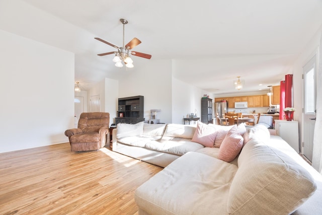 living area with light wood-type flooring, baseboards, a ceiling fan, and vaulted ceiling