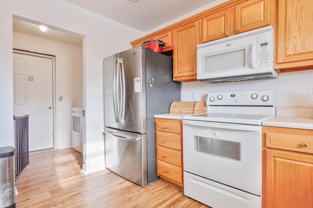 kitchen with white appliances, light countertops, and light wood-style floors