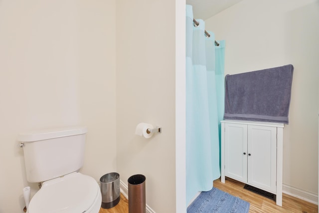 full bathroom with curtained shower, baseboards, toilet, and wood finished floors