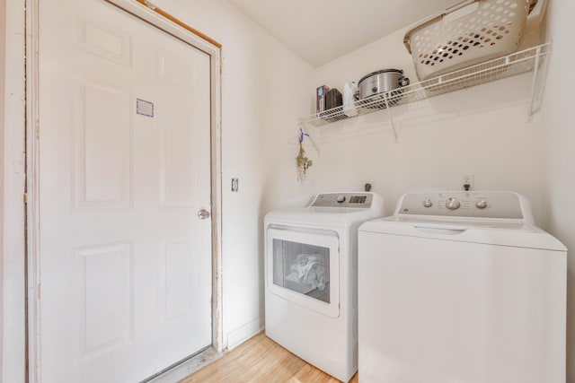 laundry area featuring light wood-style floors, baseboards, separate washer and dryer, and laundry area