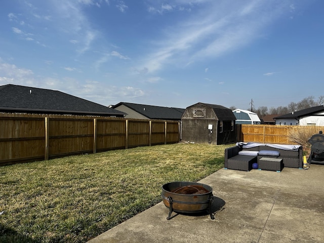 view of yard with a storage unit, a fenced backyard, an outdoor fire pit, an outdoor structure, and a patio area