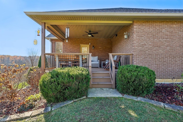 entrance to property featuring ceiling fan, a yard, and covered porch