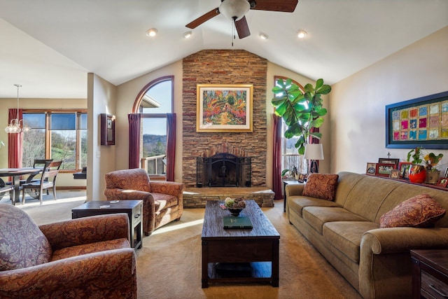 carpeted living room featuring lofted ceiling, ceiling fan with notable chandelier, and a fireplace