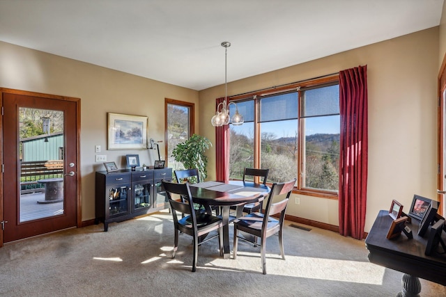 dining room featuring light carpet, a wealth of natural light, and an inviting chandelier