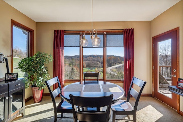 dining space featuring light carpet and an inviting chandelier