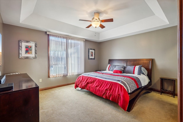 carpeted bedroom featuring a raised ceiling and ceiling fan