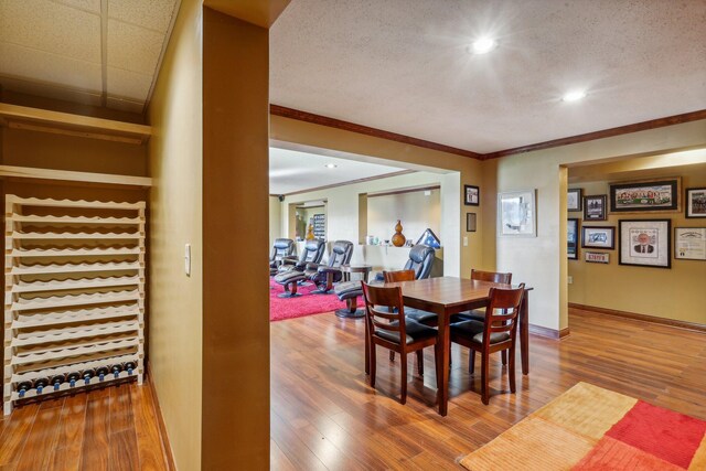 dining space with hardwood / wood-style flooring, ornamental molding, and a textured ceiling