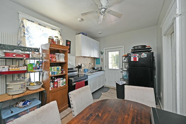 kitchen featuring sink, white cabinetry, black fridge, electric stove, and ceiling fan