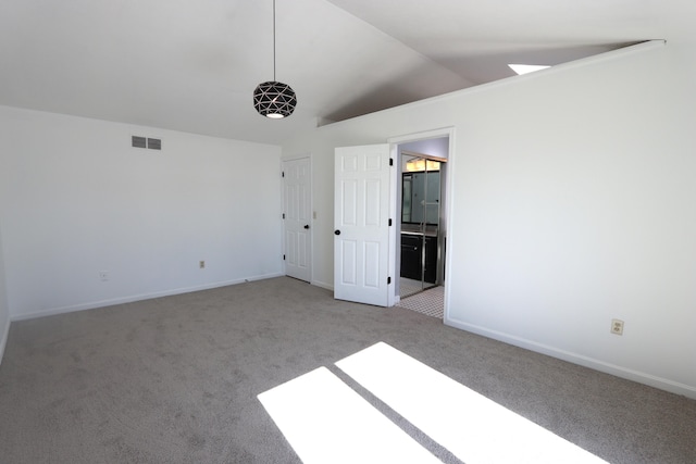 unfurnished bedroom with vaulted ceiling, connected bathroom, and light colored carpet