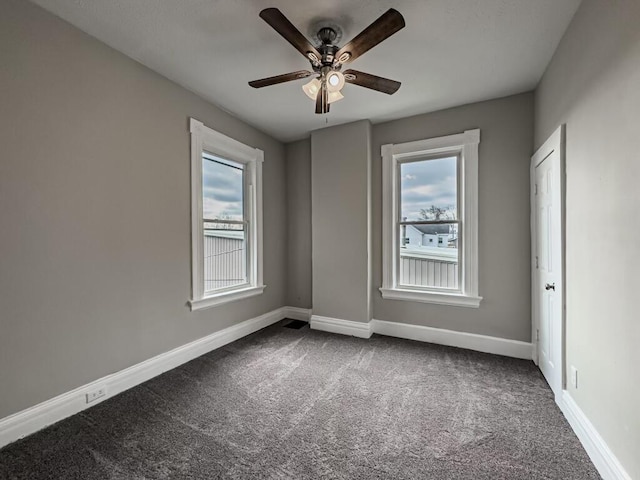 unfurnished room with dark carpet and ceiling fan