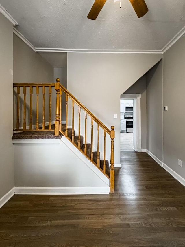 stairs featuring a textured ceiling, wood-type flooring, ornamental molding, and ceiling fan