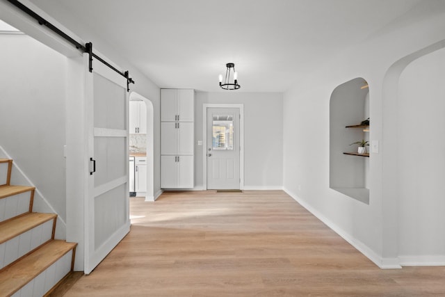 foyer entrance with a barn door and light wood-type flooring