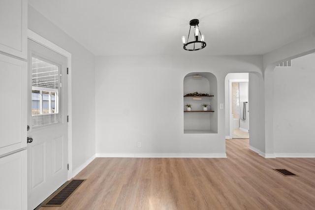 unfurnished dining area with light hardwood / wood-style flooring and a chandelier