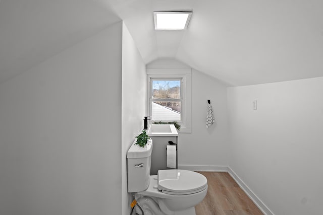 bathroom featuring sink, vaulted ceiling, hardwood / wood-style floors, and toilet