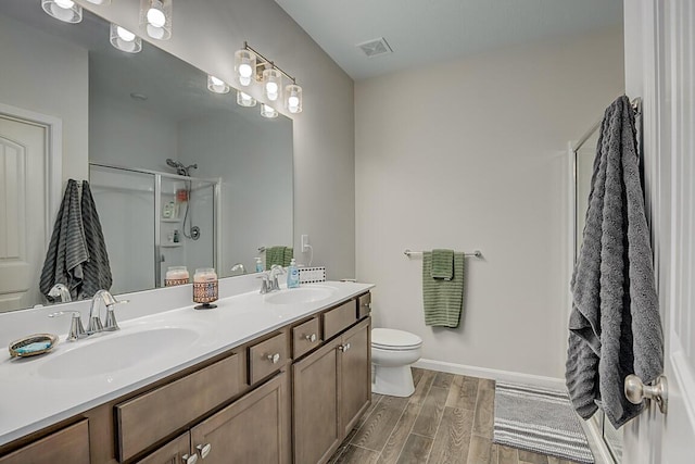 bathroom with a shower with door, wood-type flooring, vanity, and toilet