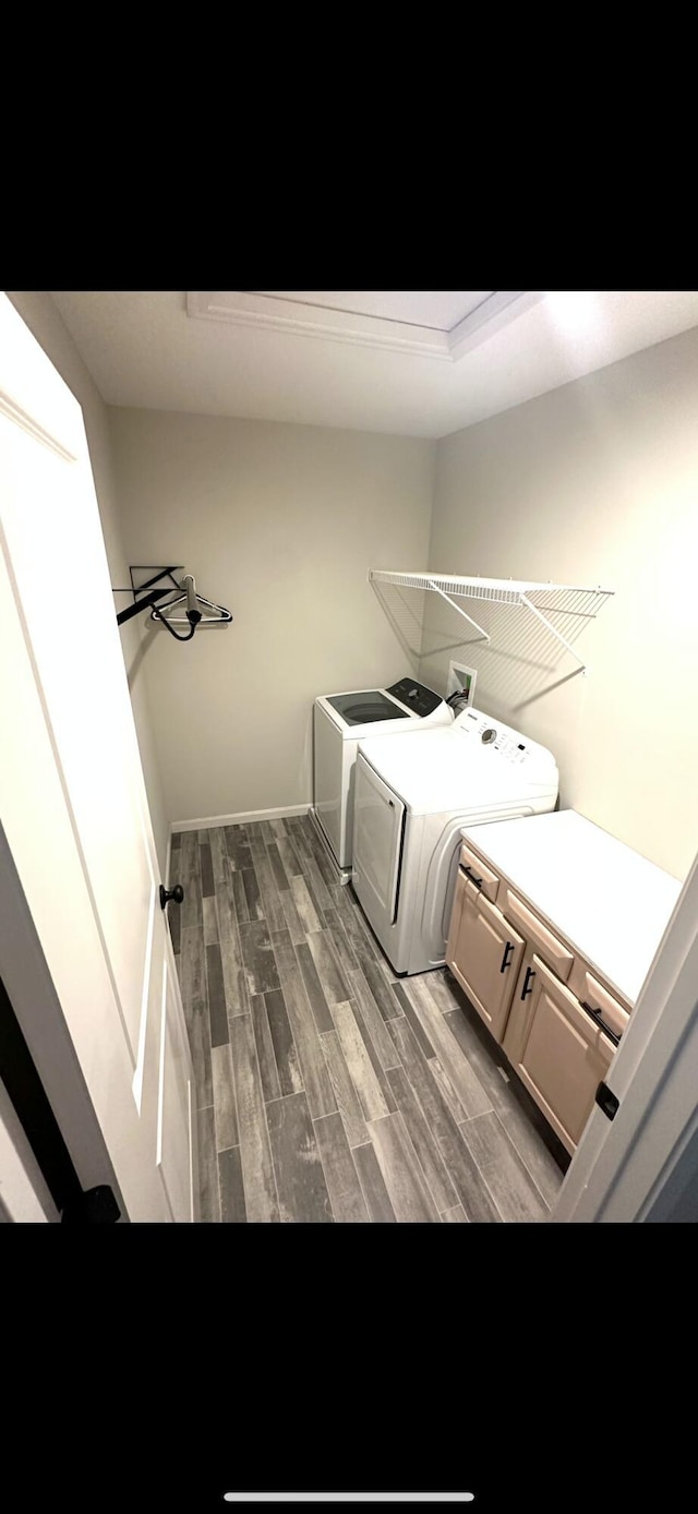 laundry area with dark wood-type flooring, cabinets, and washing machine and clothes dryer