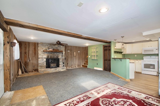 unfurnished living room featuring a fireplace, beam ceiling, wooden walls, and ceiling fan