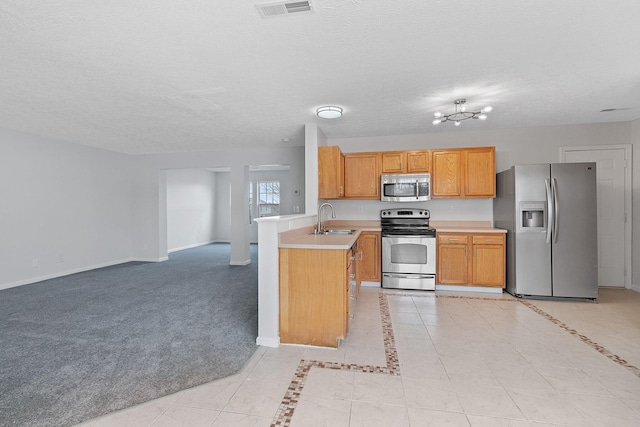 kitchen featuring sink, stainless steel appliances, a textured ceiling, light carpet, and kitchen peninsula