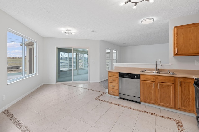 kitchen with stainless steel dishwasher, sink, a textured ceiling, and light tile patterned floors