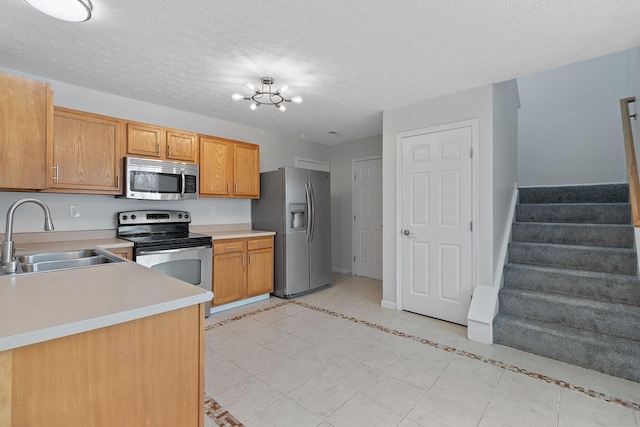 kitchen with sink, a notable chandelier, a textured ceiling, and appliances with stainless steel finishes