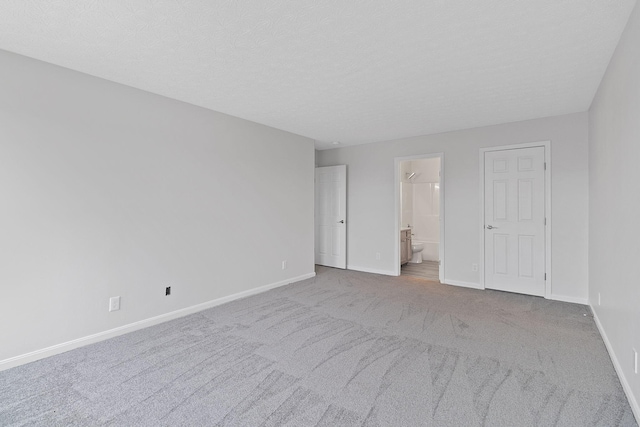 spare room featuring light carpet and a textured ceiling